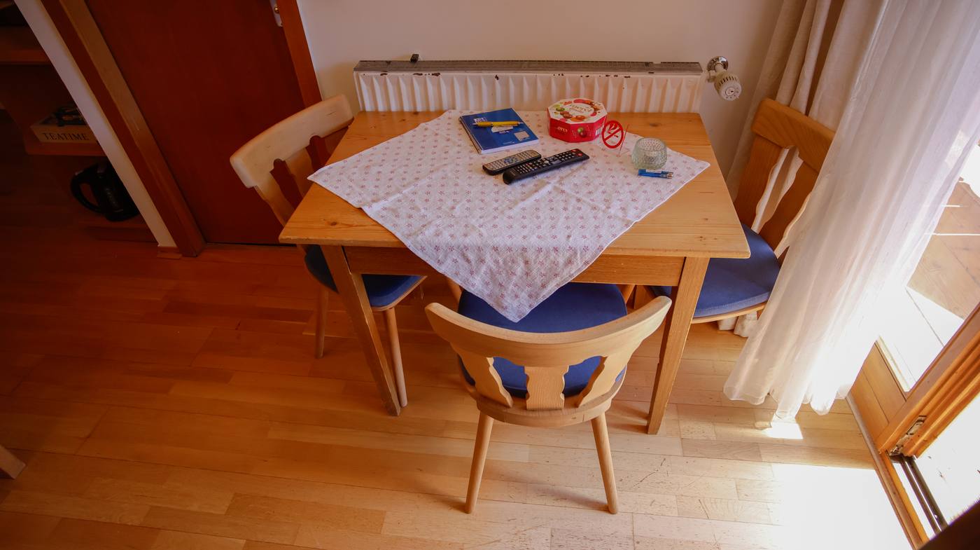 Sitzecke mit Esstisch und blauen Stühlen am Balkonfenster