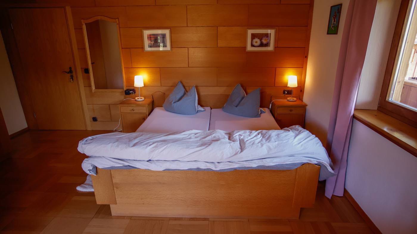 Morgensonne – Doppelbett mit Holzvertäfelung und Bildern